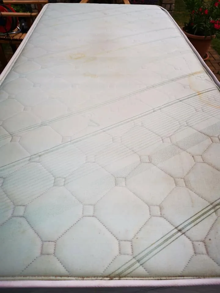 Quilted mattress photographed outdoors with visible marks before cleaning