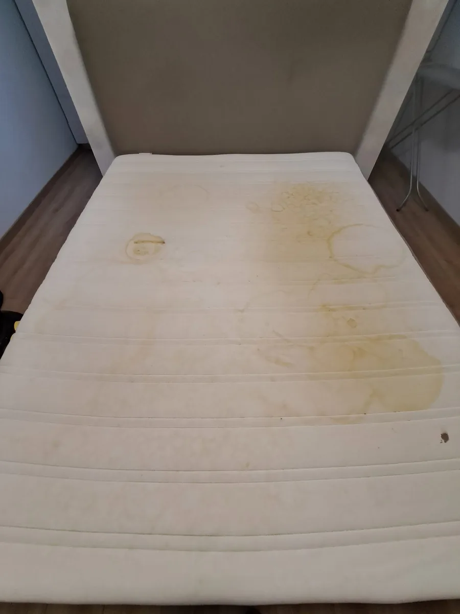 Ribbed white mattress with yellow rings and patches before cleaning
