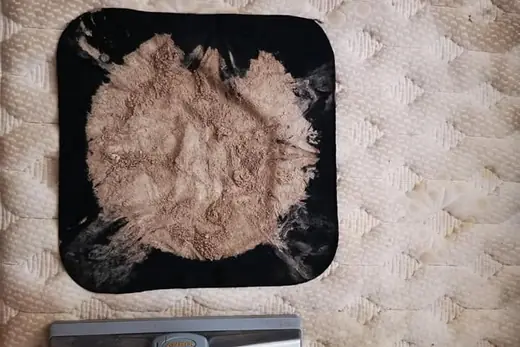 Fine grey dust collected on a dark inspection cloth on a mattress