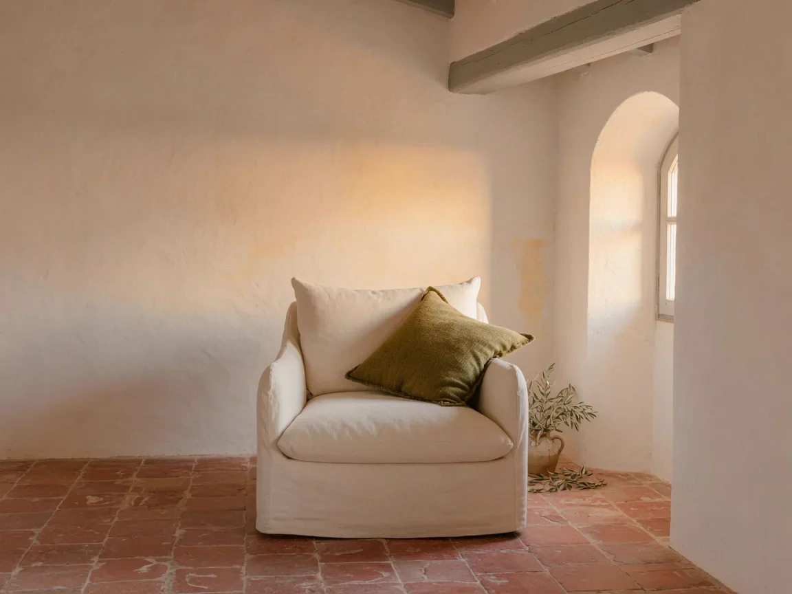 Cream fabric armchair with an olive cushion in a warm stone interior